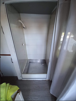 Shower cubicle in a converted motorhome with an engine coolant water heating system