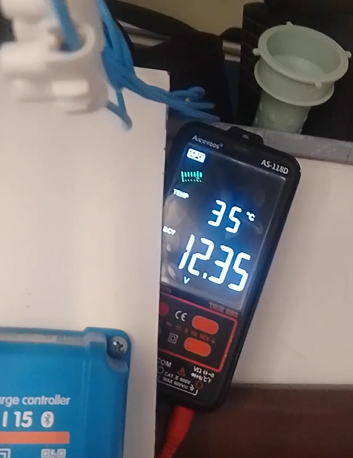 Multimeter showing 12.35V next to the solar charge controller